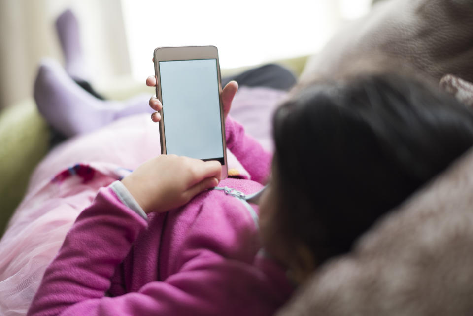 little girl looking smartphone in home indoors on sofa, empty screen concussion