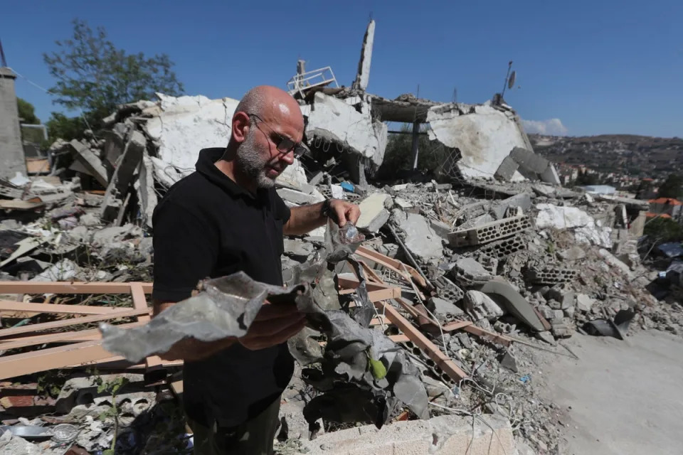 A man shows the remain of an Israeli warplane missile that hit a house and killed a Hezbollah fighter with two of his civilian family members, in Bint Jbeil town, south Lebanon (AP)