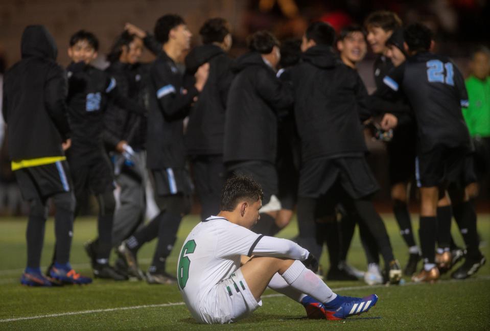 A Victor Valley player sits on the field as San Gorgonio players celebrate after pulling off a 1-0 victory in the CIF-Southern Section Division 6 championship game on Monday, Feb. 27, 2023.