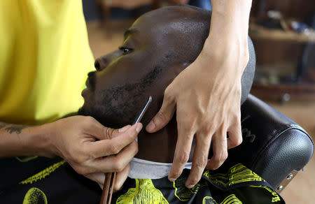 FILE PHOTO: A client looks on as he is shaved at the Bespoken Man, a full-service gentleman's barber shop in Sandton, South Africa, December 14, 2018. REUTERS/Siphiwe Sibeko