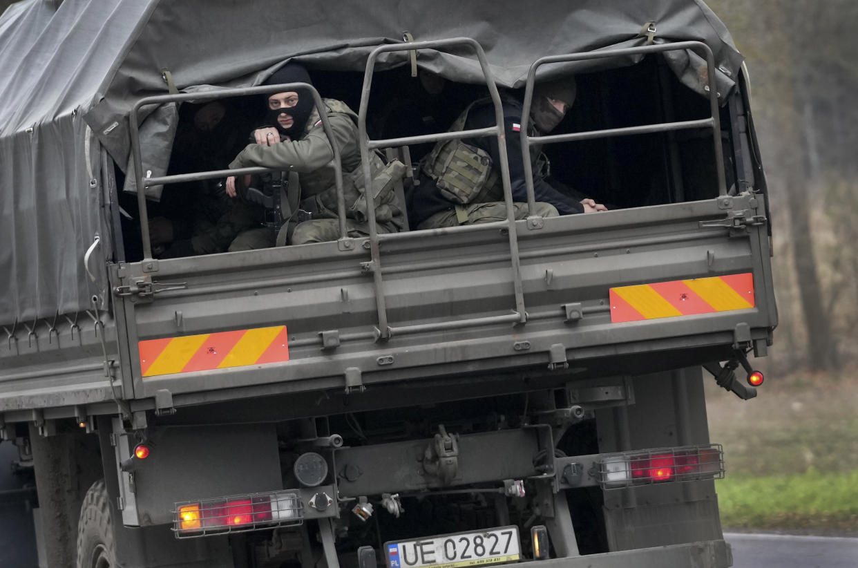 Polish soldiers sit on an army vehicle as they drive past a check point close to the border with Belarus in Kuznica, Poland, Tuesday, Nov. 16, 2021. (AP Photo/Matthias Schrader)