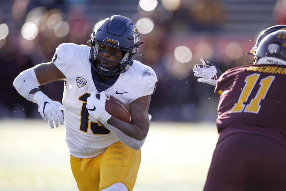 Toledo running back Peny Boone, left, eludes Central Michigan defenders during the second half of an NCAA college football game, Friday, Nov. 24, 2023, in Mount Pleasant, Mich. (AP Photo/Al Goldis)