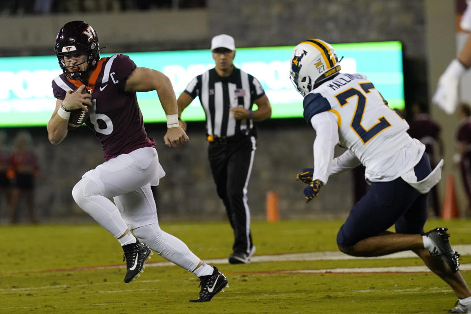 Virginia Tech quarterback Grant Wells (6) gets past West Virginia safety Davis Mallinger (27) during the first half of an NCAA college football game Thursday, Sept. 22, 2022, in Blacksburg, Va. (AP Photo/Steve Helber)