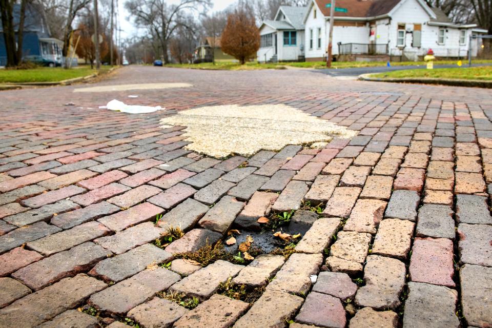 A pothole and repair patches mar the brick streets on W. Aiken Avenue at DuSable in South Peoria.