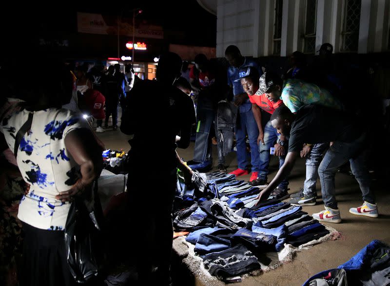 People look at clothes for sale at a roadside night market in central Harare