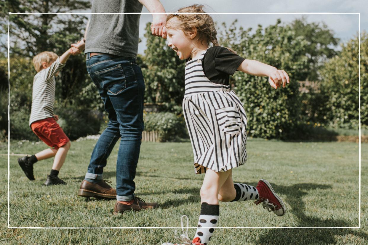  Dad playing in the garden with his kids, they are spinning around and laughing 