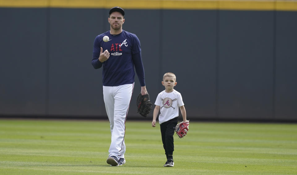 Atlanta Braves' Freddie Freeman walks with his son, Charlie, uring a workout ahead of the NLCS playoff baseball game, Thursday, Oct. 14, 2021, in Atlanta. (AP Photo/Brynn Anderson)