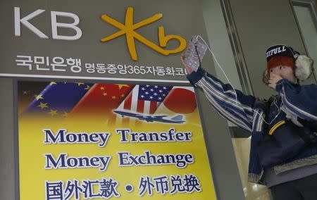 A tourist uses her smart phone at a Kookmin Bank branch in central Seoul December 5, 2012. REUTERS/Lee Jae-Won