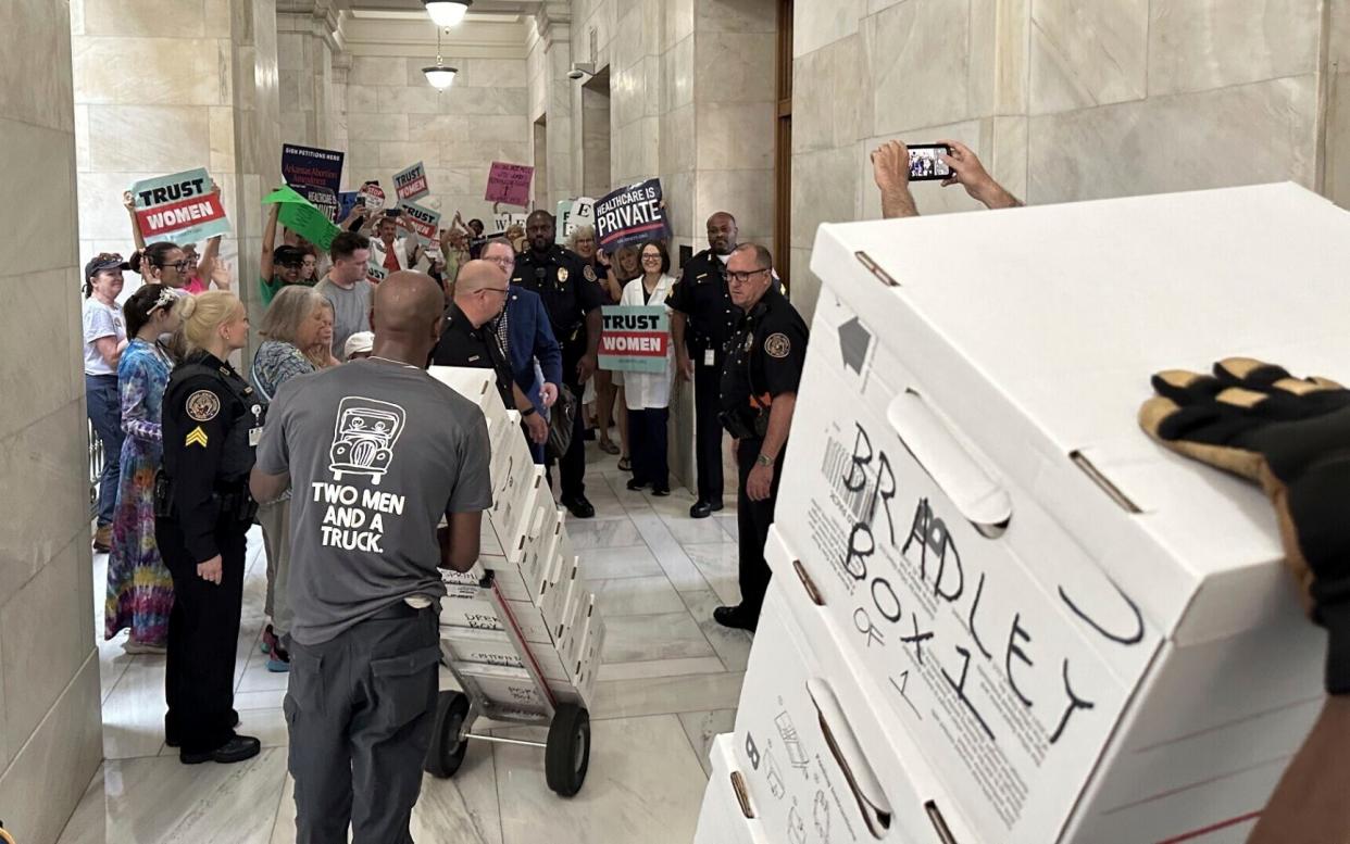 Boxes containing signatures supporting the proposed ballot measure are delivered to a room in the state Capitol