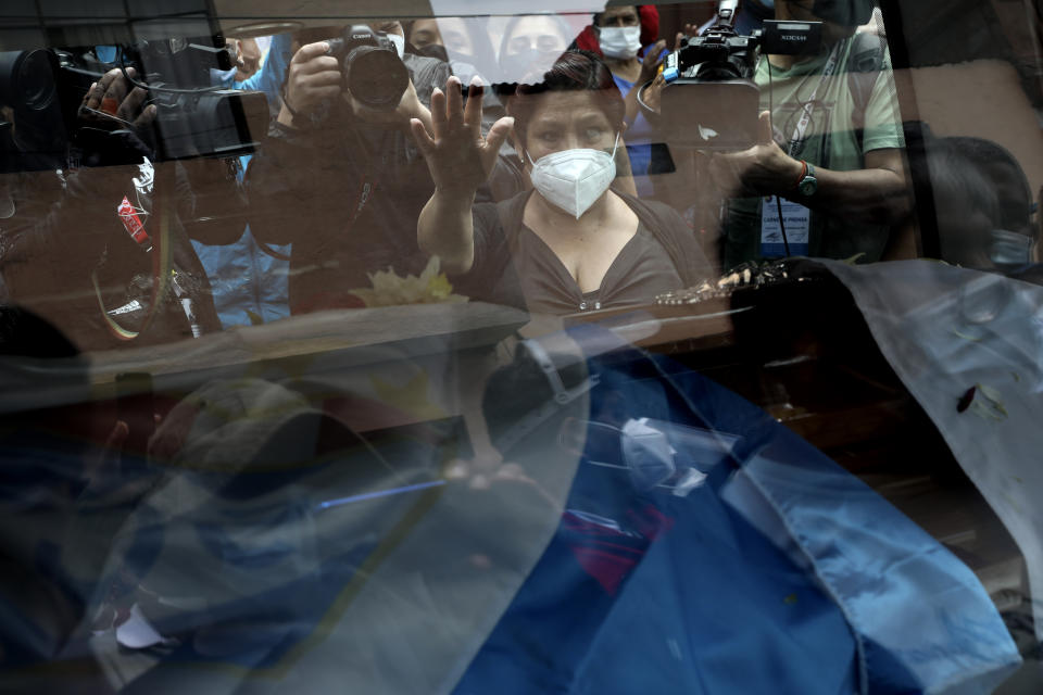 An unidentified woman touches the window of the hearse carrying the coffin of Inti Sotelo Camargo, 24, a student who died during Nov. 14 protests against lawmakers' removal of President Martin Vizcarra, as he's taken to a cemetery in Lima, Peru, Monday, Nov. 16, 2020. Peru's political turmoil took a turn Sunday when interim leader Manuel Merino quit and Congress couldn't decide on his replacement, leaving the nation without a president and in crisis less than a week after legislators removed Vizcarra. (AP Photo/Rodrigo Abd)