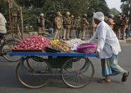 A vegetable vendor pushes his cart past police personnel standing guard on a street in Lucknow, in the northern Indian state of Uttar Pradesh, Friday, Dec. 27, 2019. Paramilitary and police forces were deployed and the internet shut down Friday in Muslim-majority districts in Uttar Pradesh, where more than a dozen people have been killed and more than 1,000 people arrested in protests that have erupted nationwide against a new citizenship law that excludes Muslims. (AP Photo/Rajesh Kumar Singh)