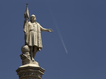 An airplane flies past a statue of Christopher Columbus in central Madrid August 3, 2011. REUTERS/Paul Hanna