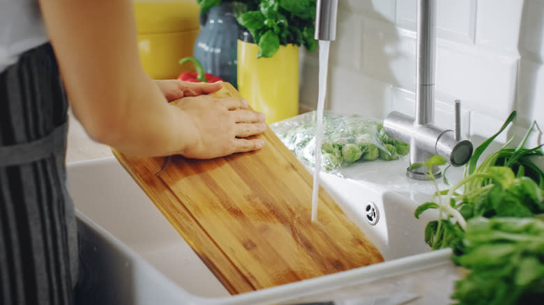 person cleaning a cutting board