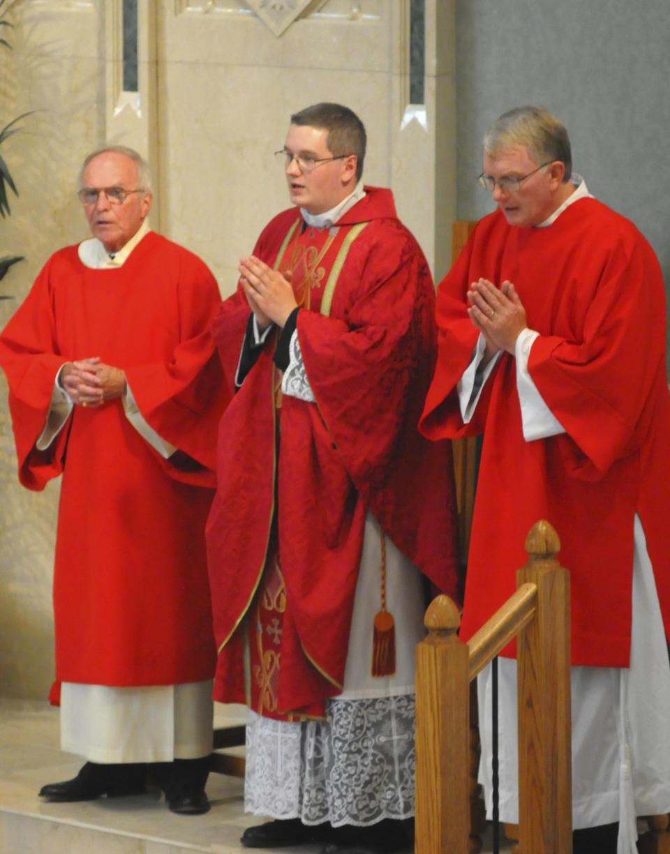 File- This June 8, 2014, file photo shows the Reverend Kevin M. Lonergan, center, who was ordained celebrated his first mass at St. Patrick's Church in Pottsville, Pa. The 30-year-old Lonergan was charged Tuesday, Aug. 21, 2018, with corruption of minors, a felony, and indecent assault. He is facing charges in connection with a 17-year-old girl he met at Mass, including allegations that he sent her nude images of himself on social media and groped her during a hug. (Andy Matsko/The Republican-Herald via AP)