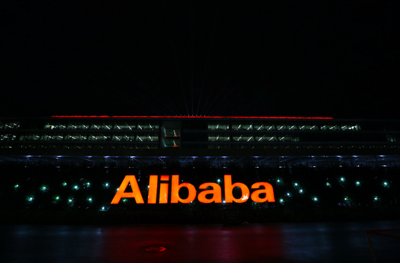 The word Alibaba lit up in orange in a nighttime photo of Alibaba's offices in China