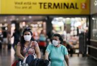 People wear protective face masks at international arrivals area at Guarulhos International Airport, amid coronavirus fears, in Guarulhos