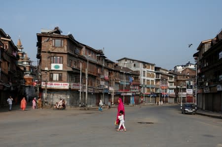 Residents cross a street during restrictions in Srinagar