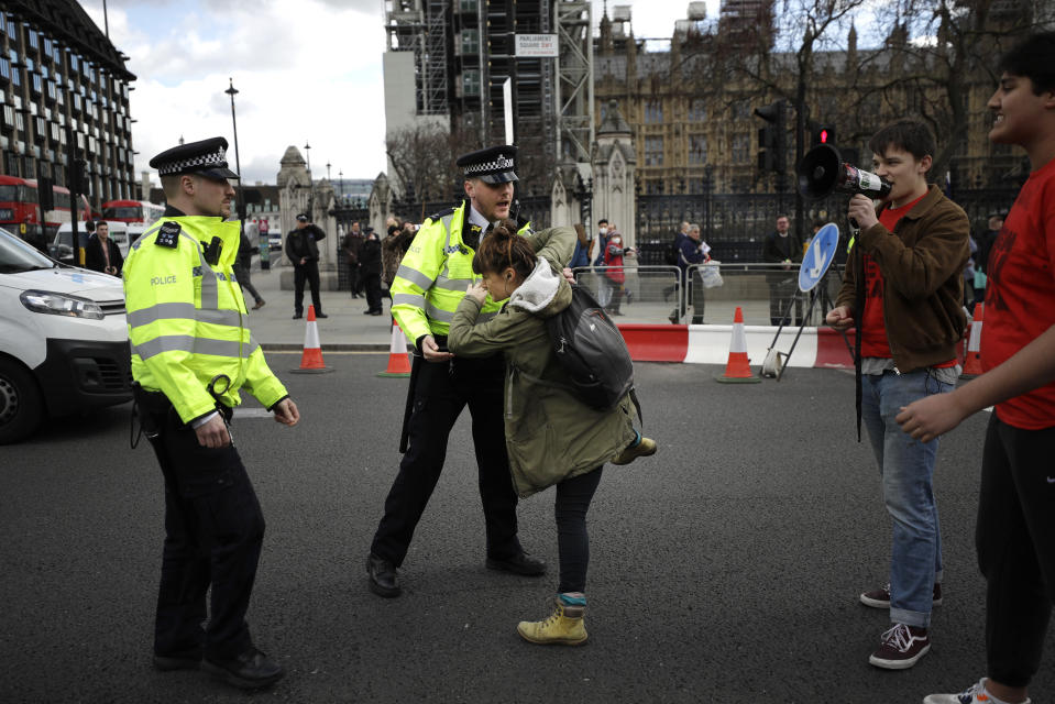 Police remove a climate change protestor from the road during a demonstration on the budget outside Parliament in London, Wednesday, March 11, 2020. Britain's Chancellor of the Exchequer Rishi Sunak will announce the first budget since Britain left the European Union. (AP Photo/Matt Dunham)