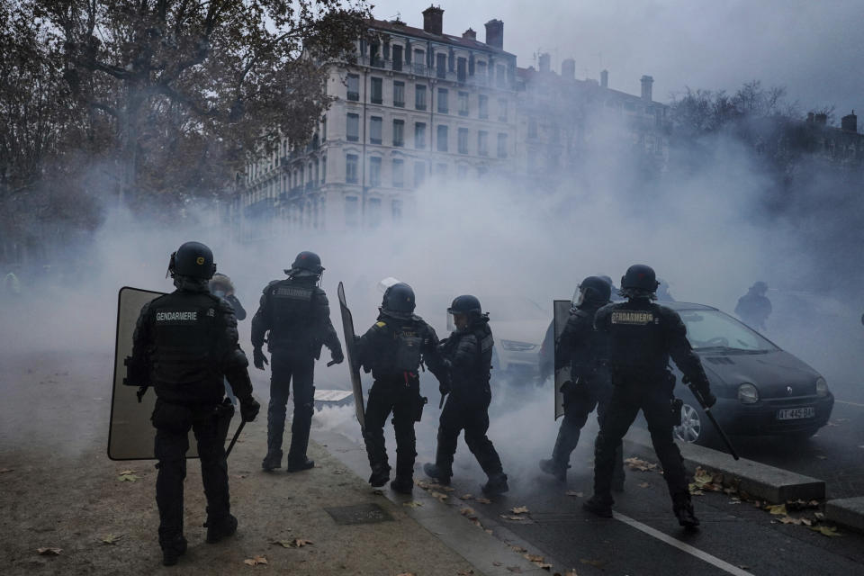 Riot police officers take position during a protest against a proposed bill, in Lyon, central France, Saturday, Dec. 12, 2020. The bill's most contested measure could make it more difficult for people to film police officers. It aims to outlaw the publication of images with intent to cause harm to police. The provision has caused such an uproar that the government has decided to rewrite it. Critics fear the law could erode press freedom and make it more difficult to expose police brutality. (AP Photo/Laurent Cipriani)