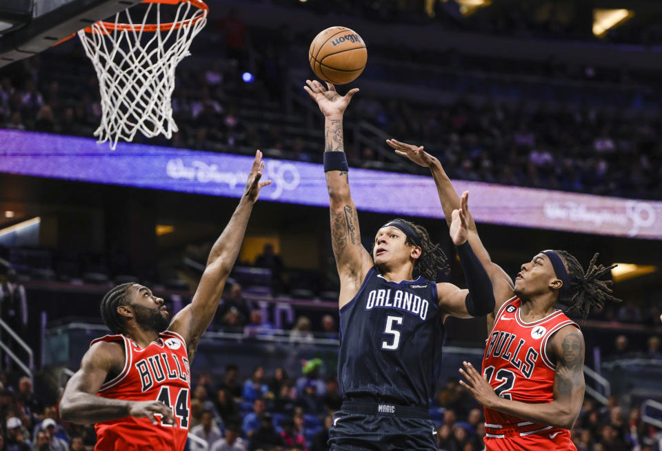 Orlando Magic forward Paolo Banchero (5) shoots from between between Chicago Bulls forward Patrick Williams (44) and guard Ayo Dosunmu (12) during the first half of an NBA basketball game Saturday, Jan. 28, 2023, in Orlando, Fla. (AP Photo/Kevin Kolczynski)