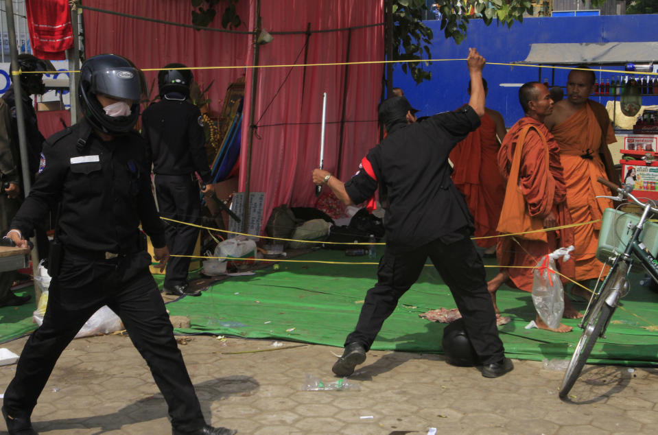 Security officers try to beat Buddhist monks who took part in a rally of the Cambodian National Rescue Party in Phnom Penh, Cambodia, Saturday, Jan. 4, 2014. Cambodian police have pushed out about 1,000 anti-government demonstrators from a park in the capital Phnom Penh, a day after four people were killed in a crackdown on a labor protest. (AP Photo/Heng Sinith)