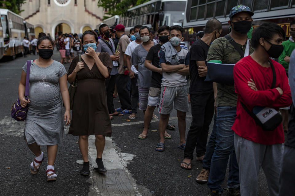 FILE PHOTO: Pregnant women walk past other Filipinos out of work and stranded due to the coronavirus pandemic as they queue to receive meals before taking a free bus ride home to their province on May 29, 2020 in Parañaque, Metro Manila, Philippines. (Photo: Ezra Acayan/Getty Images)