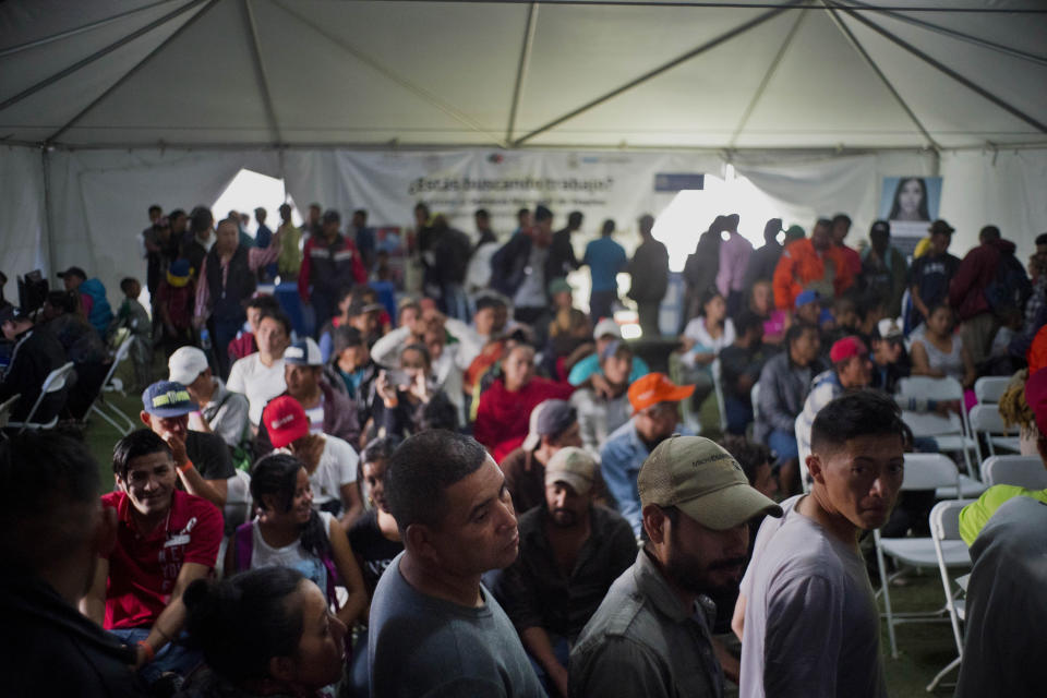 In this Nov. 27, 2018 photo, migrants who traveled in a caravan stand in line at a job fair in Tijuana, Mexico. Mexican authorities have encouraged all of the migrants to regularize their status in Mexico and seek work. (AP Photo/Ramon Espinosa)