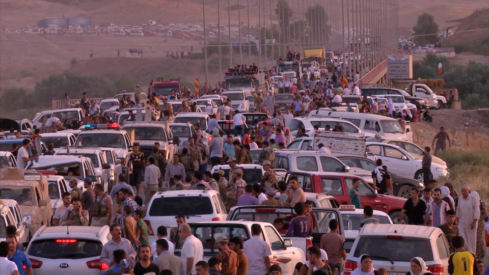 This image made from video taken on Sunday, Aug. 3, 2014 shows Iraqis people from the Yazidi community arriving in Irbil in northern Iraq after Islamic militants attacked the towns of Sinjar and Zunmar. Around 40 thousand people crossed the bridge of Shela in Fishkhabur into the Northern Kurdish Region of Iraq, after being given an ultimatum by Islamic militants to either convert to Islam, pay a security tax, leave their homes, or die. (AP Photo via AP video)