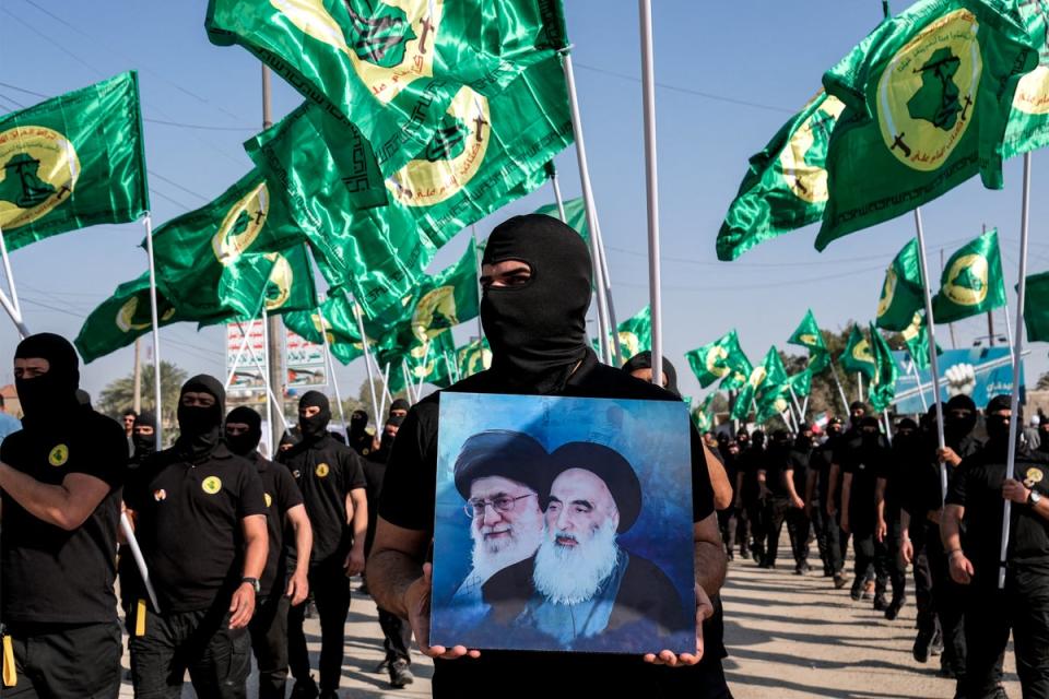 A member of an Iraqi militia holds up pictures of the former and current Iranian leaders. Ali Khamenei vowed to ‘punish’ Israel for recent attacks on Syria (AFP via Getty Images)