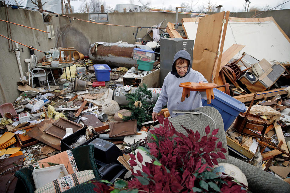 Woman looking through wreckage of home
