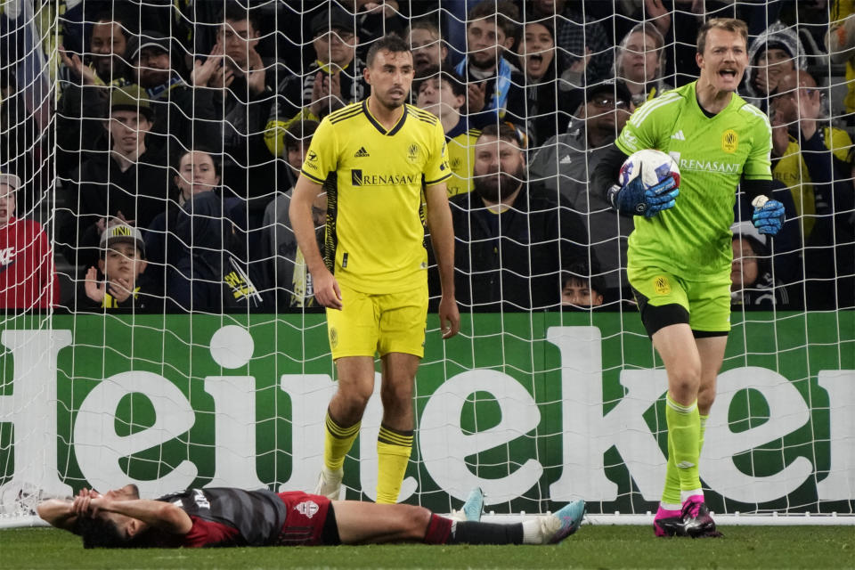 Toronto FC midfielder Jonathan Osorio lies on the pitch after Nashville SC goalkeeper Joe Willis, right, made a stop on a shot during the second half of an MLS soccer match Saturday, April 8, 2023, in Nashville, Tenn. (AP Photo/Mark Humphrey)