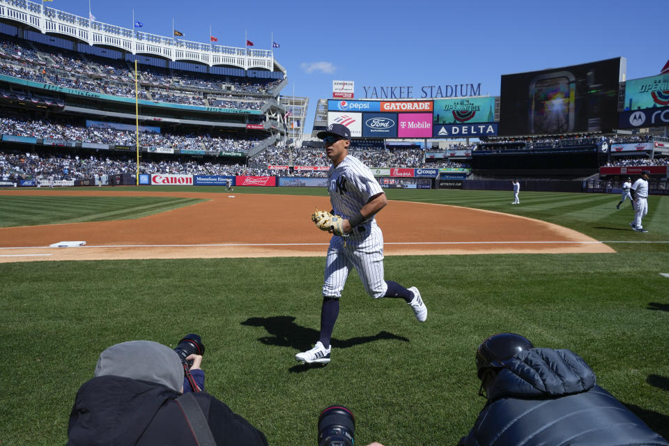 As photographers take pictures, New York Yankees' Anthony Volpe returns to the dugout after warming-up before the opening day baseball game against the San Francisco Giants at Yankee Stadium Thursday, March 30, 2023 in New York. (AP Photo/Seth Wenig)