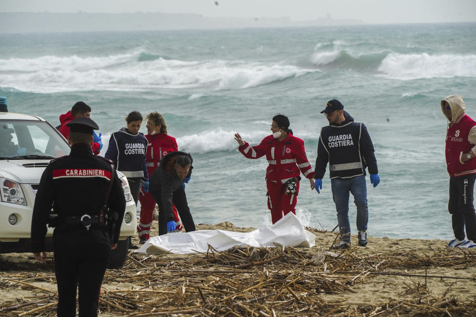 Italian Red Cross volunteers and coast guards recover a body after a migrant boat broke apart in rough seas, at a beach near Cutro, southern Italy, Sunday, Feb. 26, 2023. Rescue officials say an undetermined number of migrants have died and dozens have been rescued after their boat broke apart off southern Italy.(Antonino Durso/LaPresse via AP)