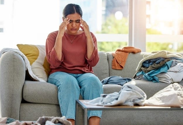 Woman on sofa stressed about the mess in her home