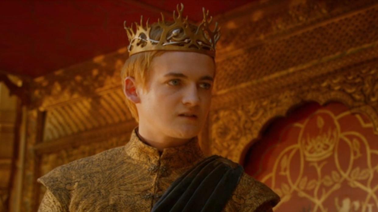  Jack Gleeson as Joffrey standing wearing a crown on Game of Thrones. 