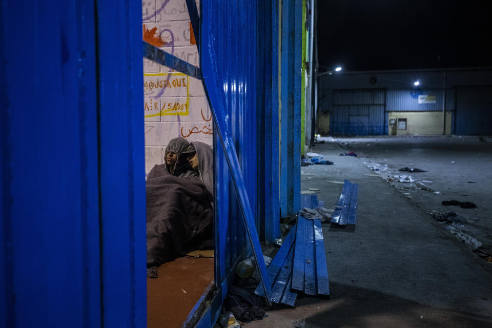 Two minors sleep inside a warehouse turned into a makeshift center for migrant minors at the Spanish enclave of Ceuta, at the border of Morocco and Spain, early Wednesday, May 19, 2021. (AP Photo/Bernat Armangue)