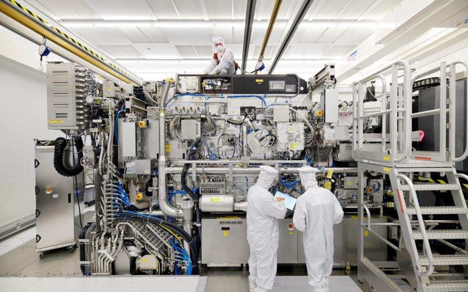 FILE PHOTO: Employees are seen working on the final assembly of ASML's TWINSCAN NXE:3400B semiconductor lithography tool with its panels removed, in Veldhoven, Netherlands, in this picture taken April 4, 2019. Bart van Overbeeke Fotografie/ASML/Handout via REUTERS/File Photo - ASML/REUTERS