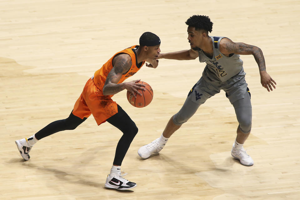 Oklahoma State guard Avery Anderson III (0) is defended by West Virginia guard Taz Sherman (12) during the first half of an NCAA college basketball game Saturday, March 6, 2021, in Morgantown, W.Va. (AP Photo/Kathleen Batten)