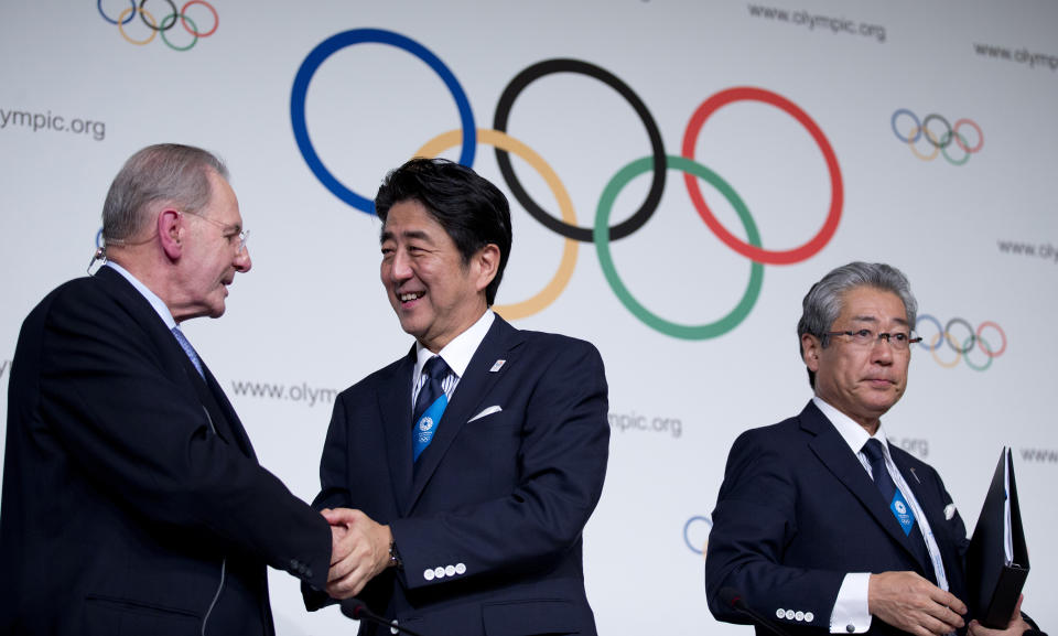 FILE- In this Sept. 7, 2013, file photo, Japan's Prime Minister Shinzo Abe, center, shakes hands with President of the International Olympic Committee Jacques Rogge as Tokyo 2020 Olympic Bid Committee President Tsunekazu Takeda stands by after signing the Host City Contract for the 2020 Olympic Games in Buenos Aires, Argentina. Abe was in the front row in 2013 in Buenos Aires when IOC President Jacques Rogge opened an envelop to show Tokyo was the 2020 host, beating out Istanbul. (AP Photo/Natacha Pisarenko)