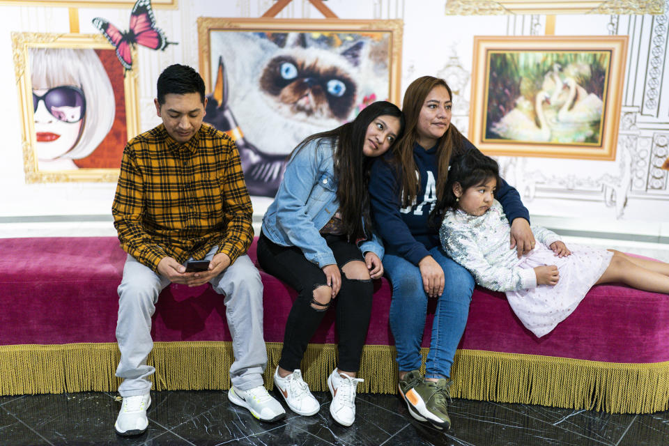 Ecuadorian migrant Klever Ortega, left, checks his phone as he visits the American Dream mall with his wife, Christina Lema, second from right, and two daughters, Josselyn, center, and Danna, 8, Saturday, March. 3, 2023, in East Rutherford, N.J. Ecuador — long known for remarkably low rates of crime, despite sitting in South America's cocaine heartland — has been struggling economically, fighting higher violence and losing its people in record numbers. Like Ortega and his family, many are headed to the U.S. (AP Photo/Eduardo Munoz Alvarez)