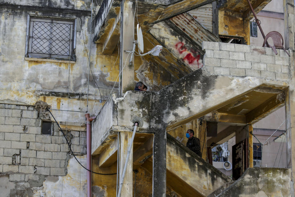 A man wearing a face mask to protect against the coronavirus walks up the stairs of an old building in the northern city of Tripoli, Lebanon, Tuesday, May 5, 2020. Lebanon should quickly form a reform-minded government to carry out badly needed reforms to help get the tiny country out of its severe economic crisis where the Real GDP growth is projected to contract nearly 20% in 2020 and a crash in local currency led to triple-digit inflation rates, the World Bank said Tuesday. (AP Photo/Hassan Ammar)