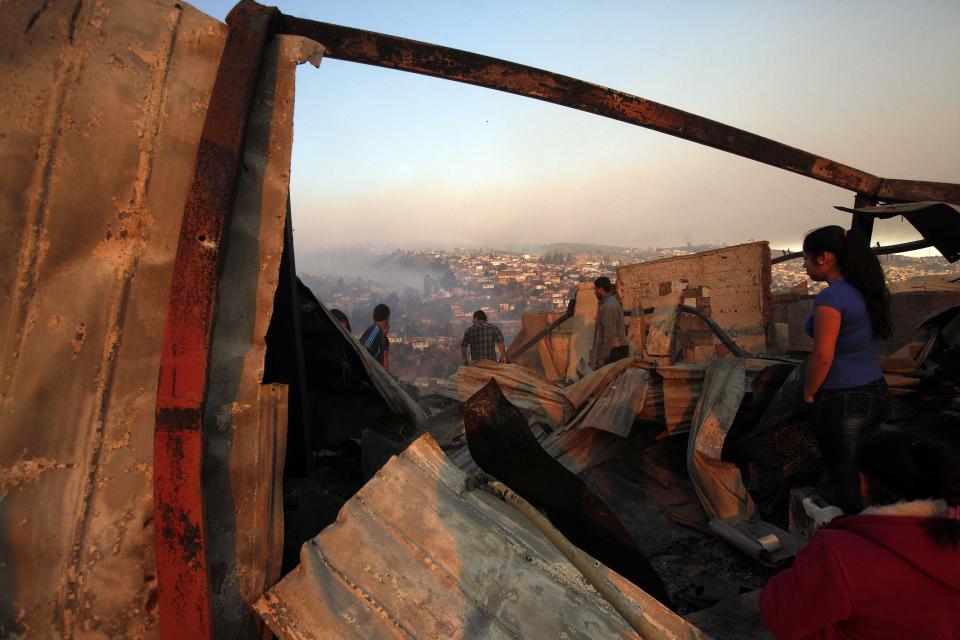 A group of people try to save items after a large forest fire reached urban areas in Valparaiso, Chile, Sunday April 13, 2014. Authorities say the fires have destroyed hundreds of homes, forced the evacuation of thousands and claimed the lives of at least seven people. ( AP Photo/ Luis Hidalgo)