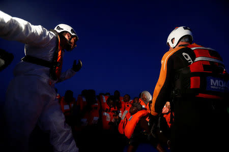 Rescuers of the Malta-based NGO Migrant Offshore Aid Station (MOAS) rescue migrants from a rubber dinghy in the central Mediterranean in international waters off the coast of Sabratha in Libya, April 15, 2017. REUTERS/Darrin Zammit Lupi