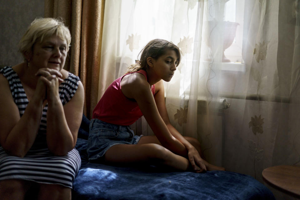 Anastasiia Aleksandrova, de 12 años, a la derecha, se sienta con su abuela, Olena, en su casa de Sloviansk, en la región de Donetsk, en el este de Ucrania, el lunes 8 de agosto de 2022. Miles de personas han evacuado a lugares seguros y las ciudades se han quedado casi vacías, de modo que los jóvenes que se que han quedado sufren soledad y aburrimiento como dolorosos contrapuntos al temor y la violencia que Moscú ha arrojado sobre Ucrania. (AP Foto/David Goldman)