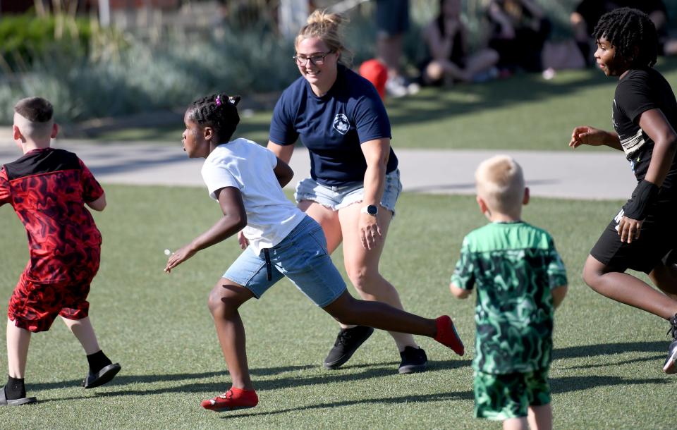 Canton police officer Nicole Jones plays football with kids during this year's first We Believe in Canton community event, which was held Wednesday at Centennial Plaza in Canton.