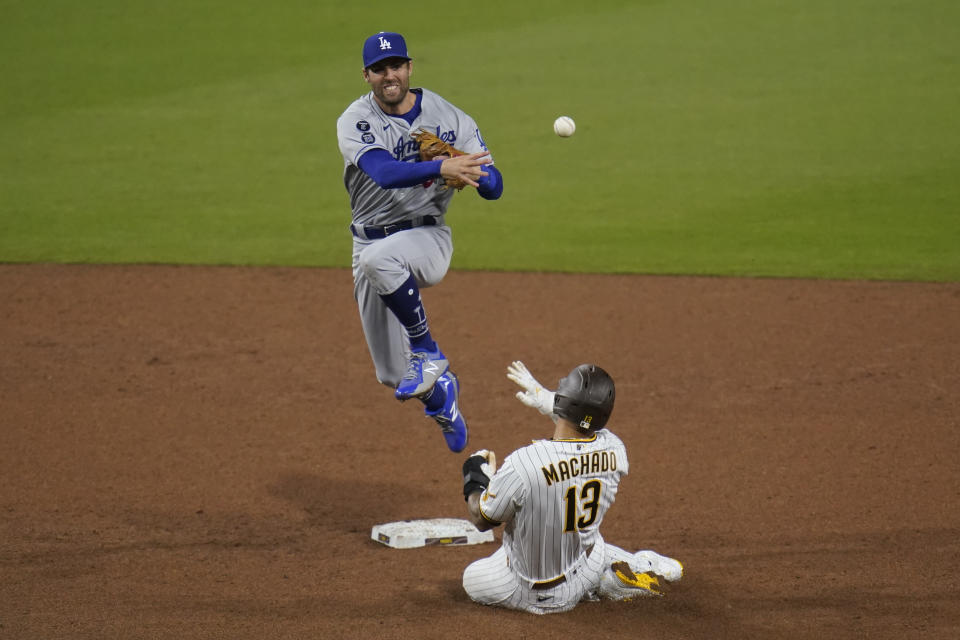 Los Angeles Dodgers second baseman Chris Taylor throws to first for the double play as San Diego Padres' Manny Machado (13) slides in late to second during the sixth inning of a baseball game Saturday, April 17, 2021, in San Diego. Wil Myers was out at first. (AP Photo/Gregory Bull)