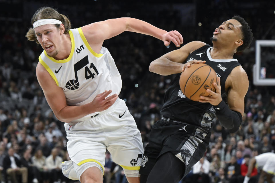 San Antonio Spurs' Keldon Johnson, right, collides with Utah Jazz's Kelly Olynyk during the first half of an NBA basketball game Tuesday, Dec. 26, 2023, in San Antonio. (AP Photo/Darren Abate)