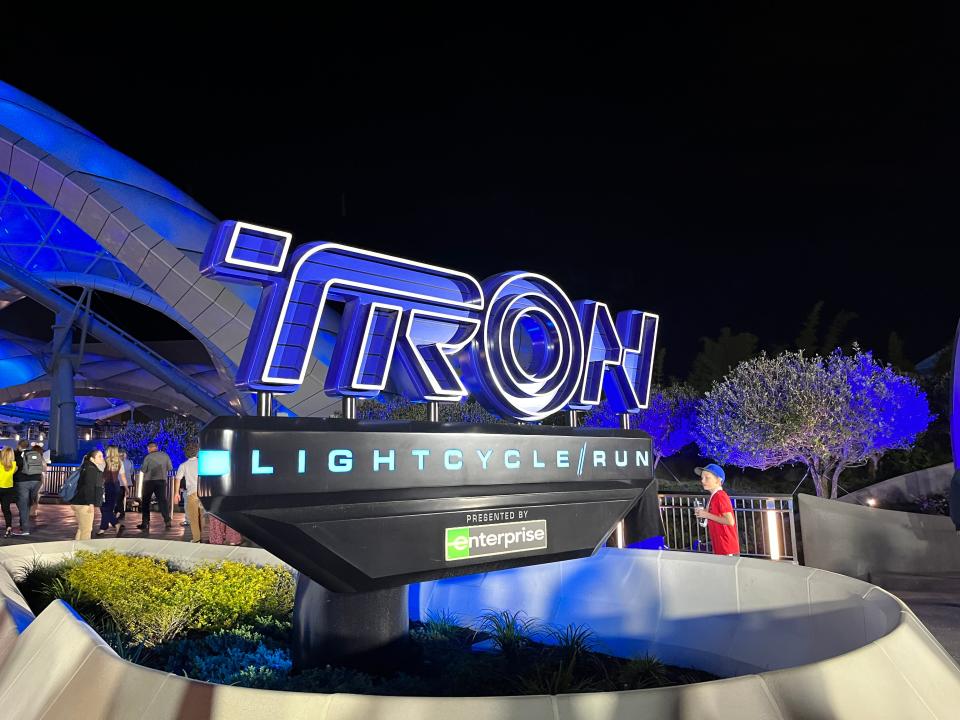 tron sign outside the magic kingdom roller coaster lit up at night