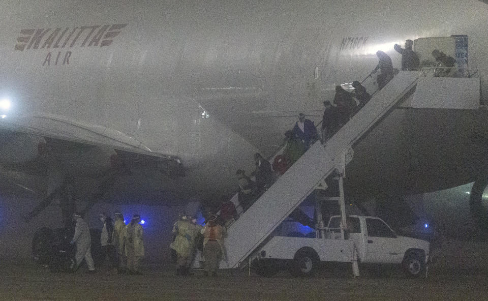 American passengers evacuated from a cruise ship in Japan disembark from a Kalitta Air flight at Kelly Field, early Monday, Feb. 17, 2020 in San Antonio, Texas. The U.S. said it arranged the evacuation because people on the Diamond Princess were at a high risk of exposure to the new virus that's been spreading in Asia. For the departing Americans, the evacuation cuts short a 14-day quarantine that began aboard the cruise ship Feb. 5. (William Luther /The San Antonio Express-News via AP)