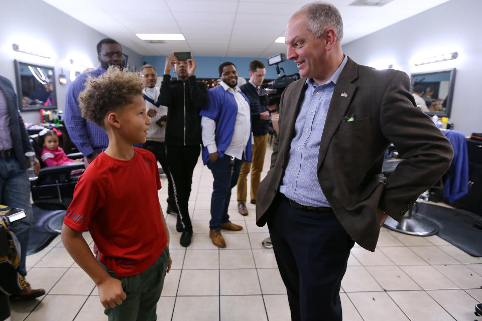 A young person talks with Louisiana Gov. John Bel Edwards in a barber shop. 